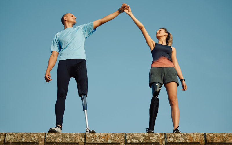 Image of 2 athletes with physical impairments standing next to each other